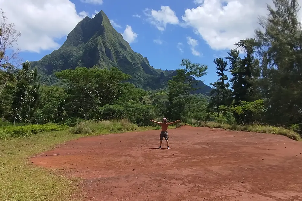 Le plateau du Bounty à Moorea Un homme vu de loin ecarte les bras face au mont Rotui en arrière plan