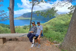 Couple sitting on a bench during the Magic Mountain hike with Mount Rotui and Moorea’s lagoon in the background