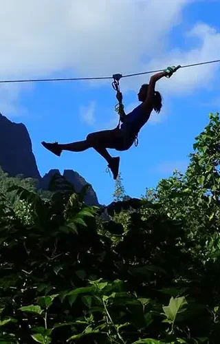 Une personne s'amuse sur une tyrolienne du parc aventure et accrobranche du Tiki Parc à Moorea