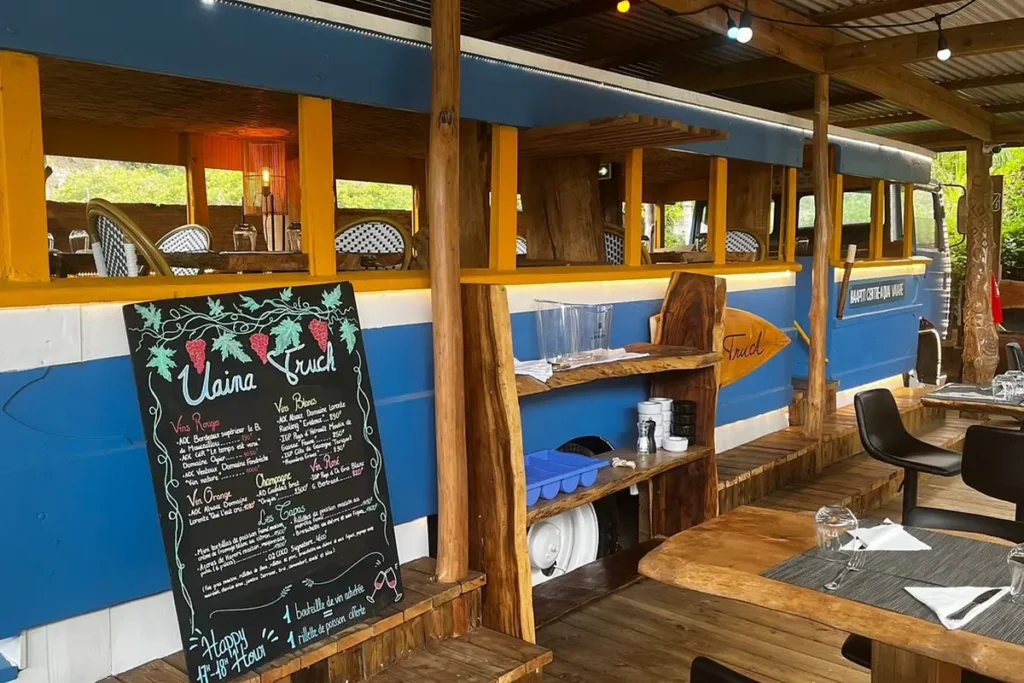 Vue extérieur d'un vieux bus tahitien bleu reconverti en restaurant à Moorea. Des tables y sont installées à l'extérieur et à l'intérieur