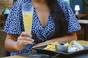 Guest holding a local Hoa drink during lunch at Uaina O2 Coco restaurant in Moorea