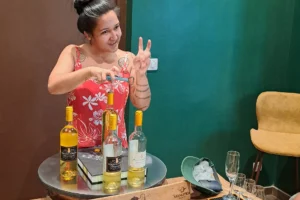 Guide présentant une bouteille de vin blanc d’ananas pendant une dégustation privée à l’usine Rotui de Moorea