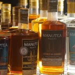Des bouteilles de rhum Manutea Tahiti posées sur une étagère de la salle dégustation privée dans l'usine Rotui à Moorea