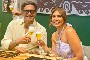 Couple souriant avec des verres de dégustation dans la salle VIP Rotui Manutea à Moorea