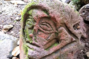Visage sculpté dans une pierre volcanique sur le Sentier des Ancêtres à Moorea