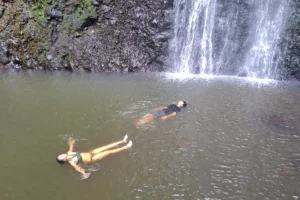 Enfants flottant dans le bassin naturel au pied de la cascade de la Vaioro à Afareaitu, Moorea
