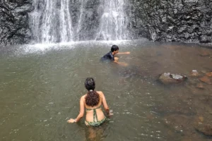 Enfants nageant dans le bassin d’eau douce au pied de la cascade de la Vaioro à Moorea