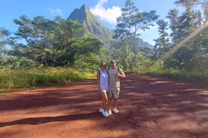 Couple posant sur la terre rouge du plateau du Bounty devant les montagnes du centre de Moorea