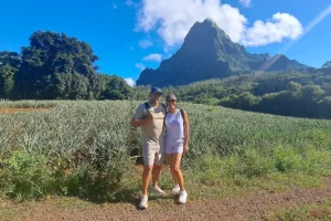 Couple posant au milieu des champs d’ananas avec les montagnes d’Opunohu en arrière-plan à Moorea