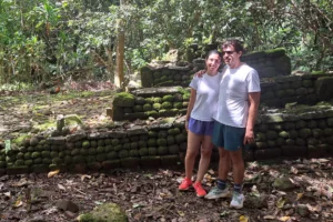 Couple posant devant un marae en pierres volcaniques pendant une visite guidée culturelle dans la vallée d’Opunohu