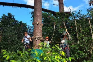 Enfants et adultes sur des ateliers suspendus entre les arbres du Tiki Parc à Moorea