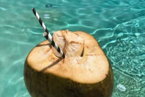 Noix de coco ouverte avec une paille au-dessus de l’eau turquoise du lagon de Moorea