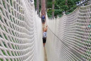 Jeune participante avançant dans un tunnel de filet suspendu entre les arbres au Tiki Parc