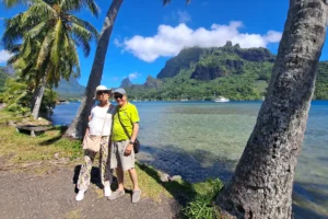 Deux visiteurs posant au bord du lagon sous les cocotiers de la baie de Cook à Moorea