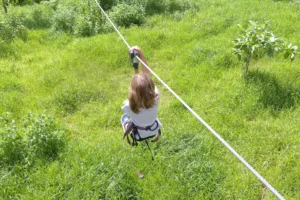 Enfant glissant sur une tyrolienne au-dessus d’un espace vert du Tiki Parc à Moorea