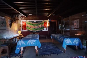Deux tables de massage éclairées en soirée dans l’espace Taurumi décoré de paréos polynésiens à Moorea