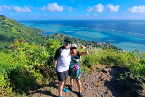 Couple on the heights of Magic Mountain overlooking the turquoise lagoon and barrier reef