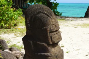 Petite sculpture tiki en pierre avec lagon turquoise de Pineapple Beach en arrière-plan à Moorea