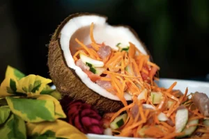 Poisson cru tahitien avec légumes et lait de coco servi dans une demi-noix de coco à Moorea
