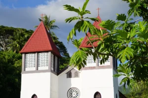 Close-up of the two red bell towers and rose window of Sainte-Famille Church in Haapiti