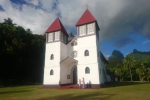Sainte-Famille Church in Haapiti with its white and red towers beneath a cloudy Moorea sky