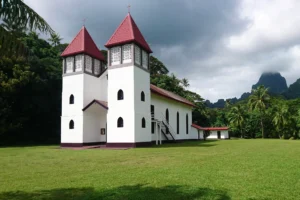 Side view of Sainte-Famille Church in Haapiti with a volcanic peak in the background