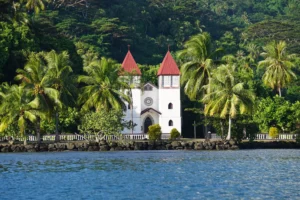 Sainte-Famille Church in Haapiti surrounded by palm trees and seen from the lagoon during a Moorea excursion