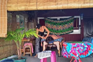 Homme recevant un massage relaxant sur une terrasse tropicale décorée de paréos à Moorea