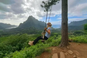 Child on the 3 Pinus swing with Mount Rotui in the background in Moorea