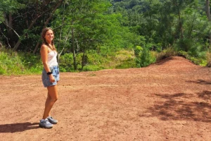 Woman walking on the red earth of Bounty Plateau during a private hike in Moorea