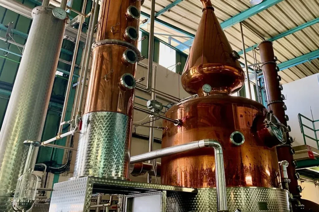 Vue en contre-plongée du grand alambic de l'usine Manutea Rotui à Moorea. Photo prise lors d'une visite publique de l'usine