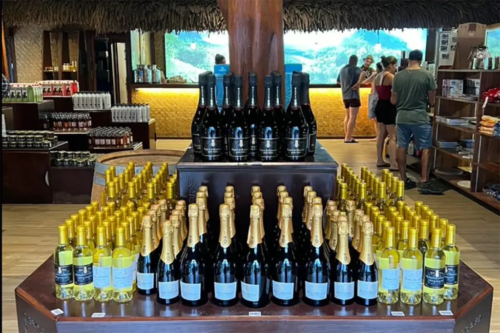 Vue de l'intérieur de la boutique d'usine Rotui et Manutea. Des bouteilles de champagne et vins d'ananas sont posées sur des présentoirs en bois
