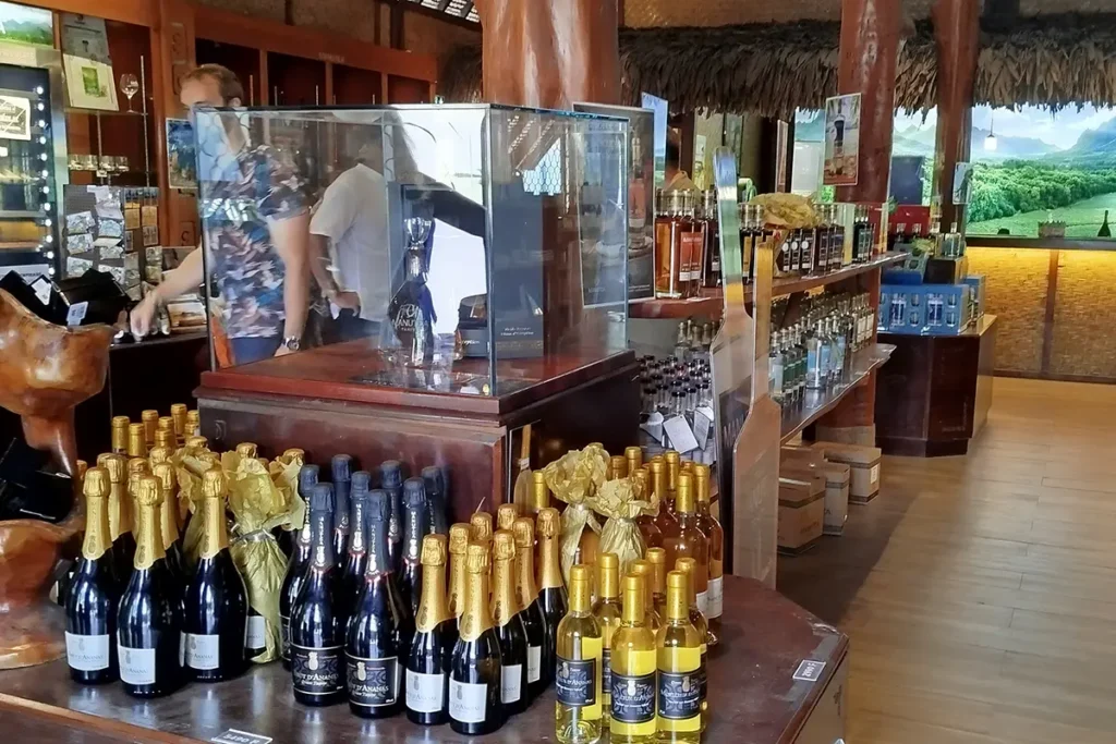 Vue de l'intérieur de la boutique d'usine Rotui et Manutea. Des bouteilles de champagne et vins blanc d'ananas sont posées sur des présentoirs en bois