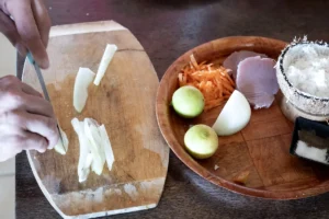 Une personne prépare un plat tahitien à base d'oignon et de noix de coco