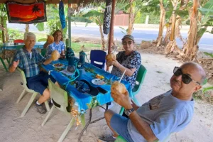 Petit groupe de visiteurs buvant de l’eau de coco fraîche à une table pendant un tour privé à Moorea