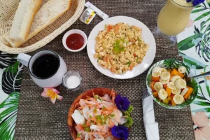 Table de petit déjeuner avec poisson cru, œufs brouillés, fruits, pain, café et jus au Fare Tutava à Moorea