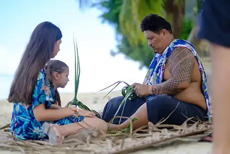 A Tahitian man weaving a coconut palm frond during a cultural immersion workshop in Moorea.