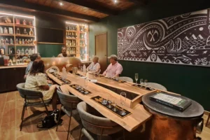 Petit groupe assis autour du long comptoir de la salle VIP Manutea pendant une dégustation à Moorea