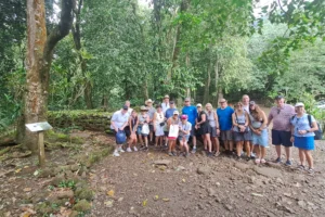 Group of visitors beside an ancient stone marae beneath mape trees in Opunohu Valley, Moorea