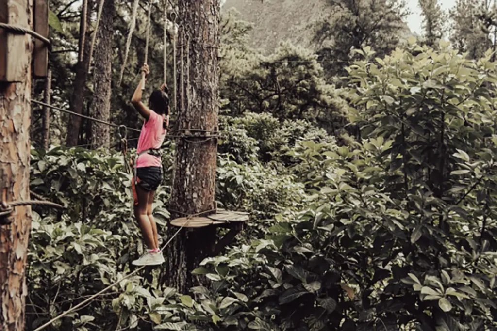 Une jeune fille tahitienne exécute un parcours d'accrobranche dans les arbres en hauteur