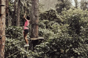 Une jeune fille tahitienne exécute un parcours d'accrobranche dans les arbres en hauteur