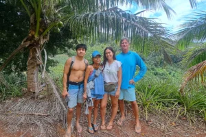 Group of four visitors beneath a coconut palm in the pineapple fields of Opunohu Valley in Moorea