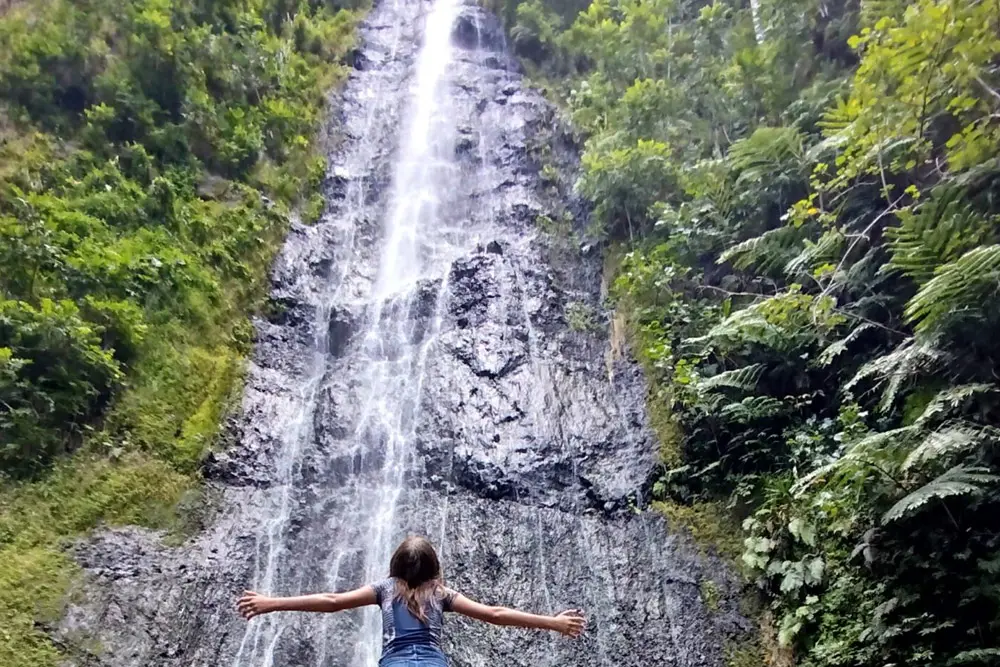 Une jeune fille se tient debout face à la cascade de Afareaitu à Moorea