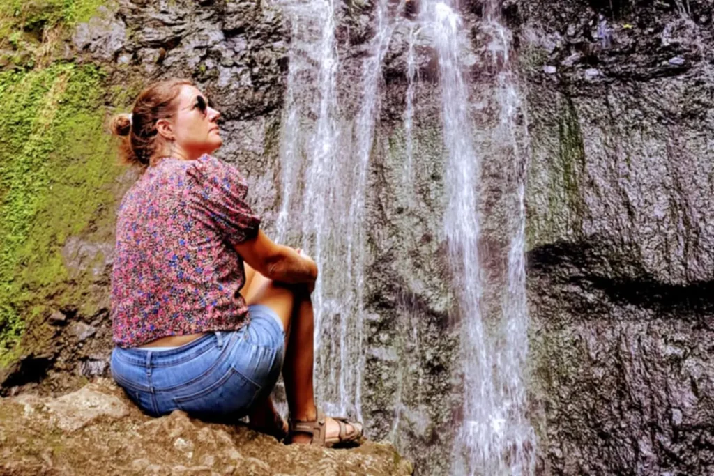 Une jeune femme assise devant la cascade de la Vaioro à Afareaitu à Moorea